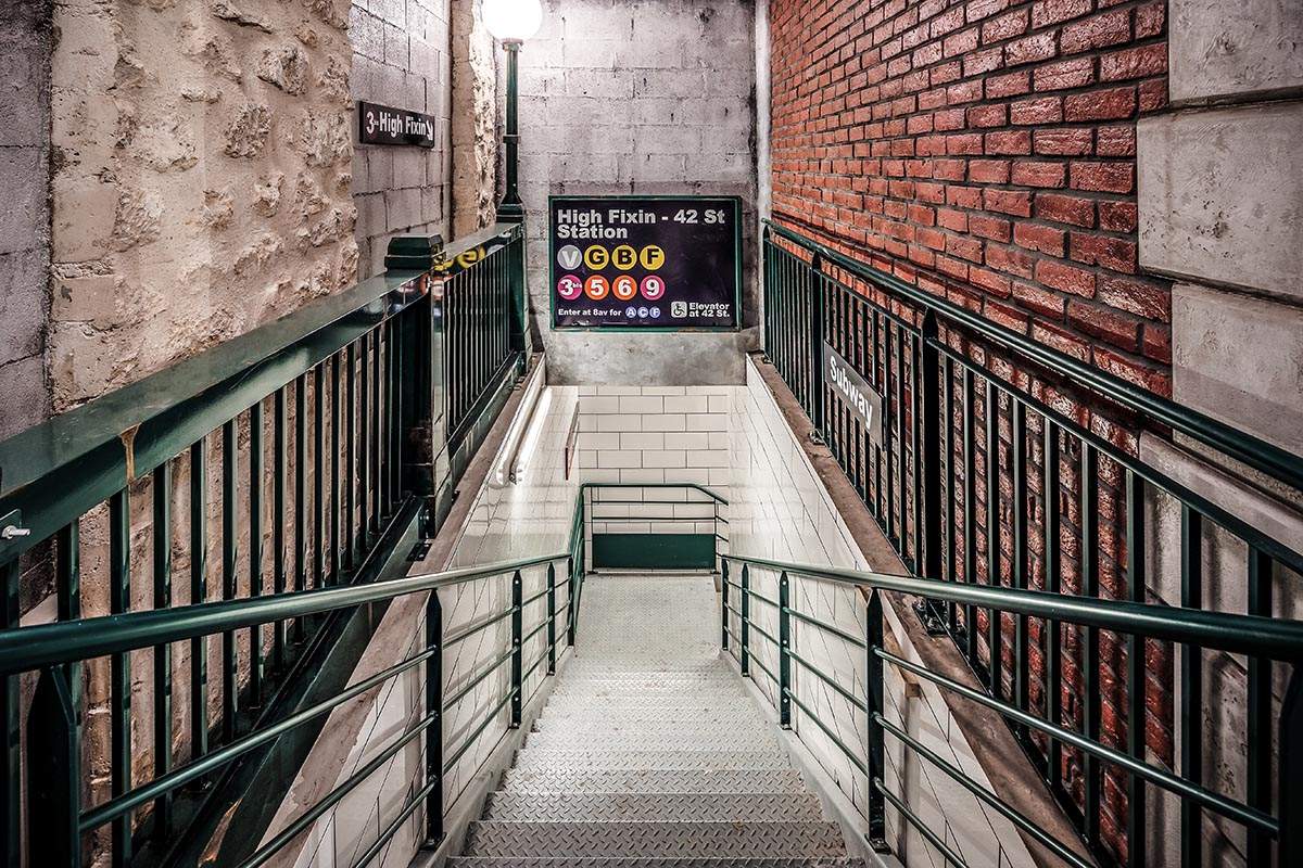 Photo de l'escalier menant du RDC au sous-sol, décoré comme une entrée de métro new-yorkais