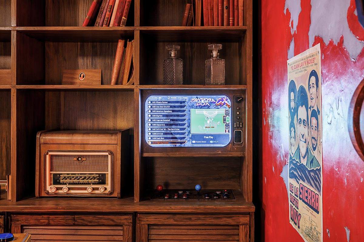 Photo de notre salon privatif Cuba - Zoom sur la bibliothèque coloniale et la borne de retro-gaming intégrée dedans