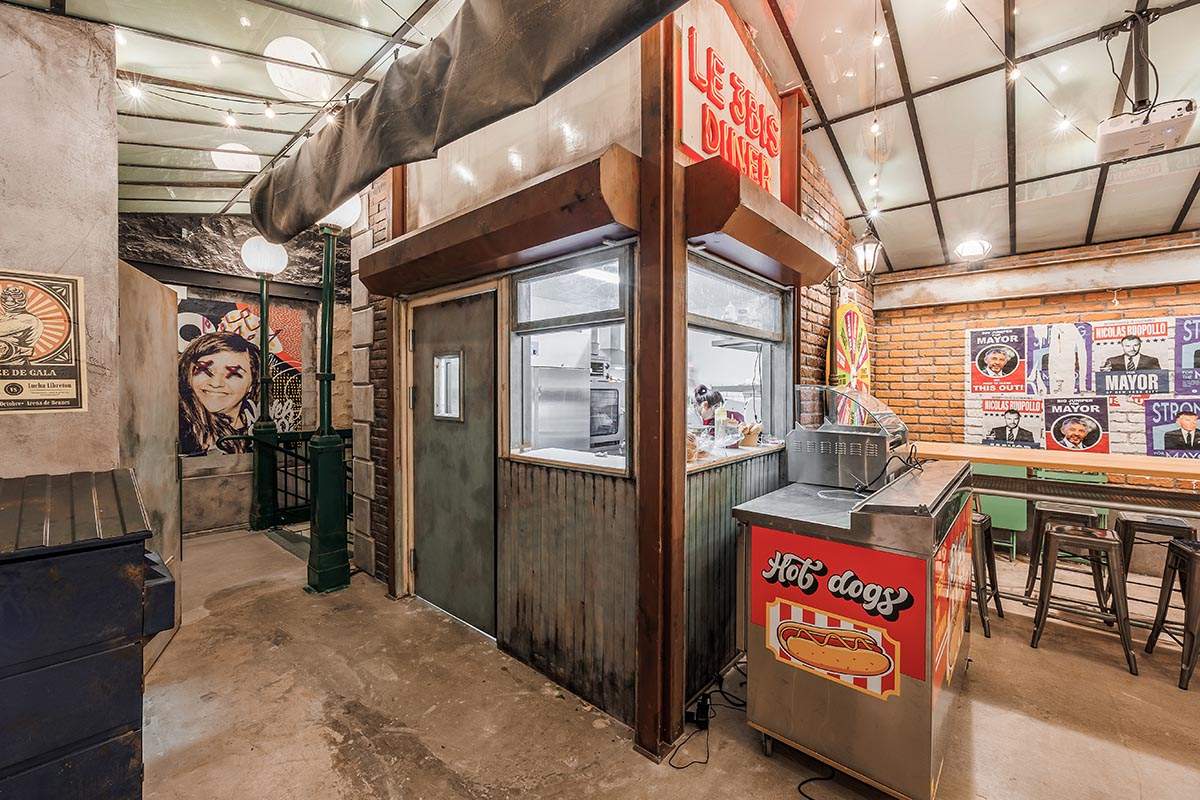 Photo de la cuisine, décorée comme un célèbre drugstore new-yorkais (BLOC Drugstore). Néon "Le 3Bis Diner", kiosque à hot-dog.