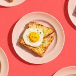 Tartines de brunch au jambon et fromage gratiné, surmontées d’un œuf au plat au jaune coulant et de ciboulette, servies avec une salade verte assaisonnée. 🍳🥗
